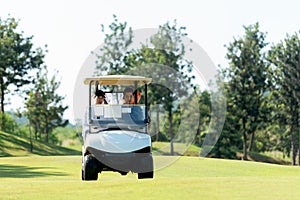 Golfer sport course golf ball on green grassÃÂ  People lifestyle man and friend siting on car golf in fairway.ÃÂ 